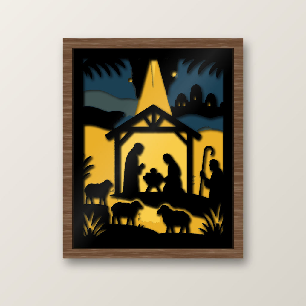 Layered nativity shadow box showing black silhouettes of Mary, Joseph and baby Jesus in a stable beneath a glowing golden Bethlehem star, with shepherds, sheep and a distant town against a blue and gold night sky.