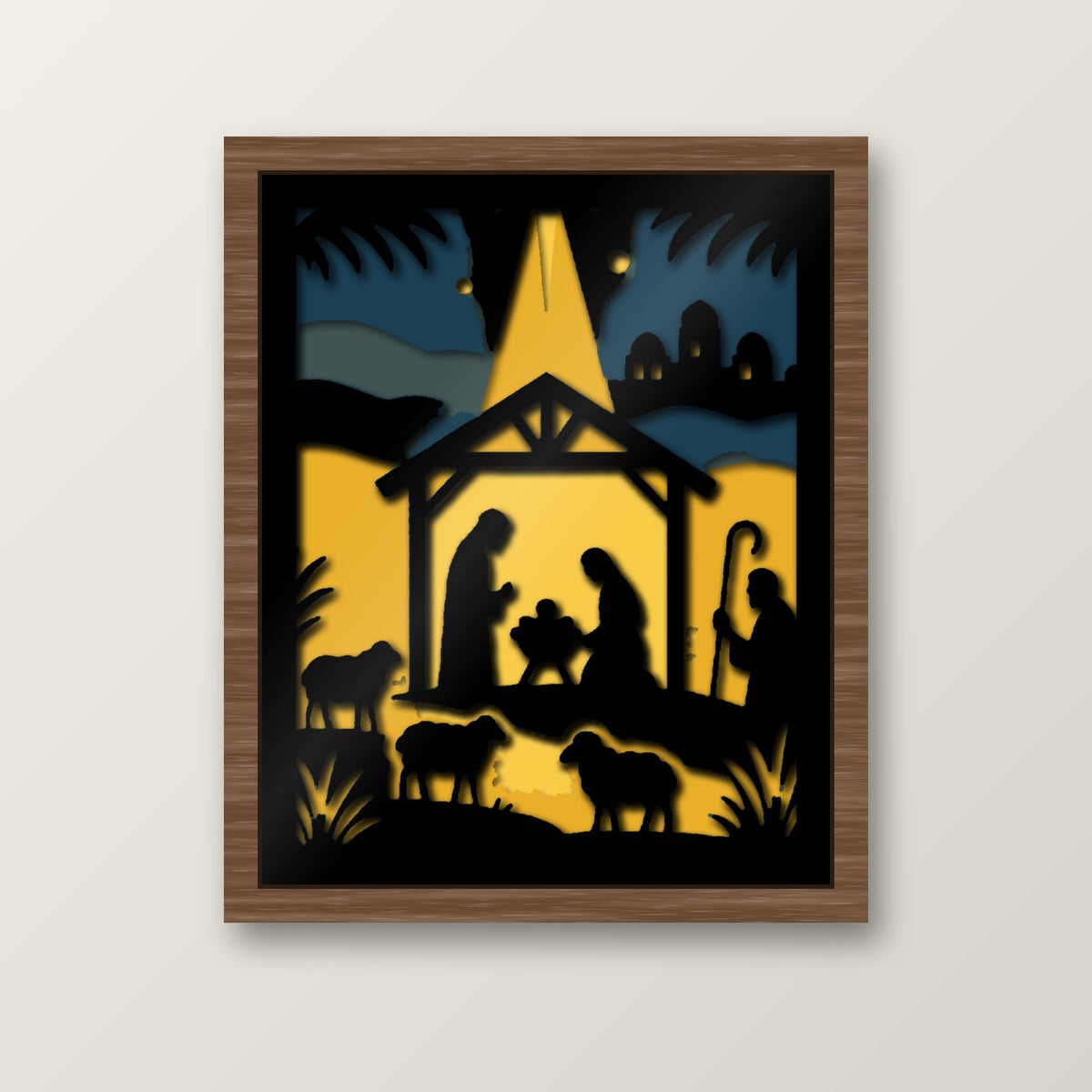 Layered nativity shadow box showing black silhouettes of Mary, Joseph and baby Jesus in a stable beneath a glowing golden Bethlehem star, with shepherds, sheep and a distant town against a blue and gold night sky.