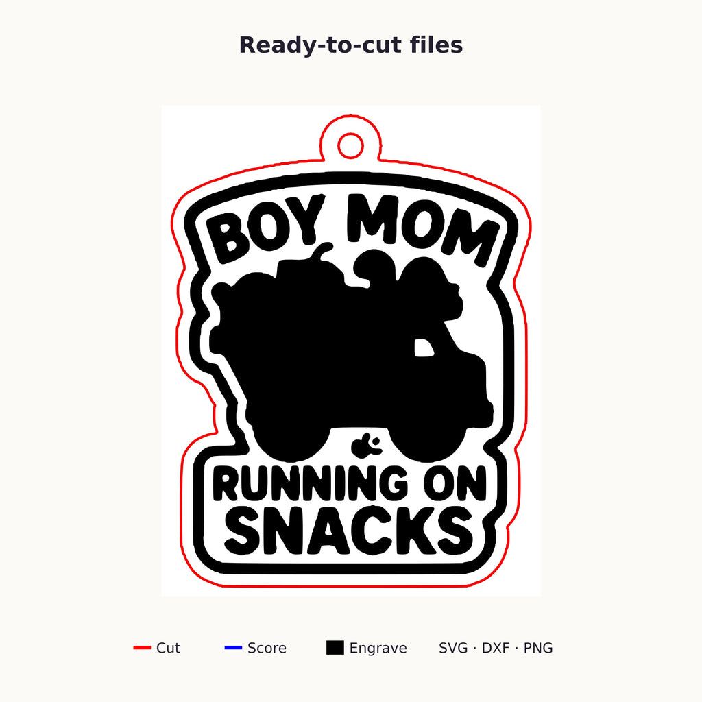Laser cut wooden ornament engraved with the words Boy Mom Running On Snacks around a brown loaded truck silhouette, hanging on a thin cord against a blurred dark green background.