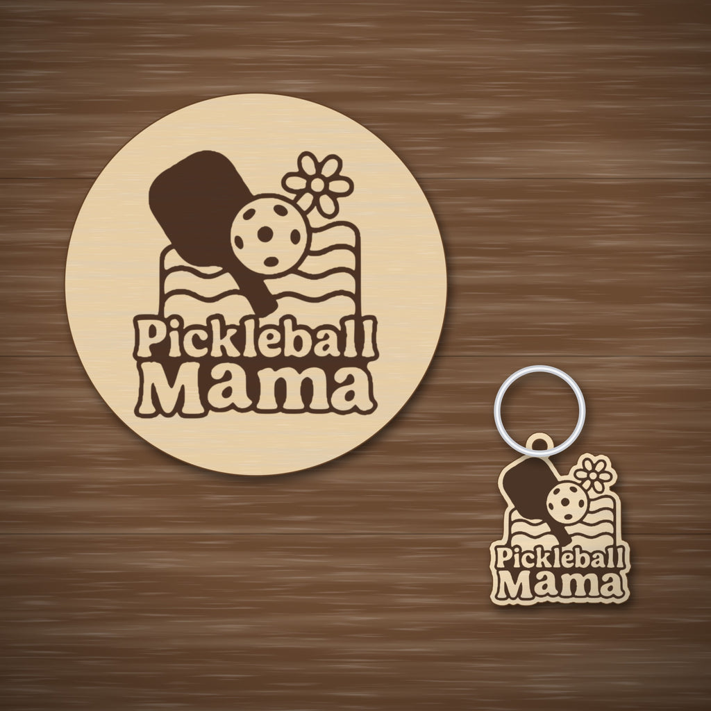 A wooden laser cut ornament with a groovy engraved pickleball paddle, ball, daisy and wavy lines above the words Pickleball Mama, hanging on a dark green bokeh background.