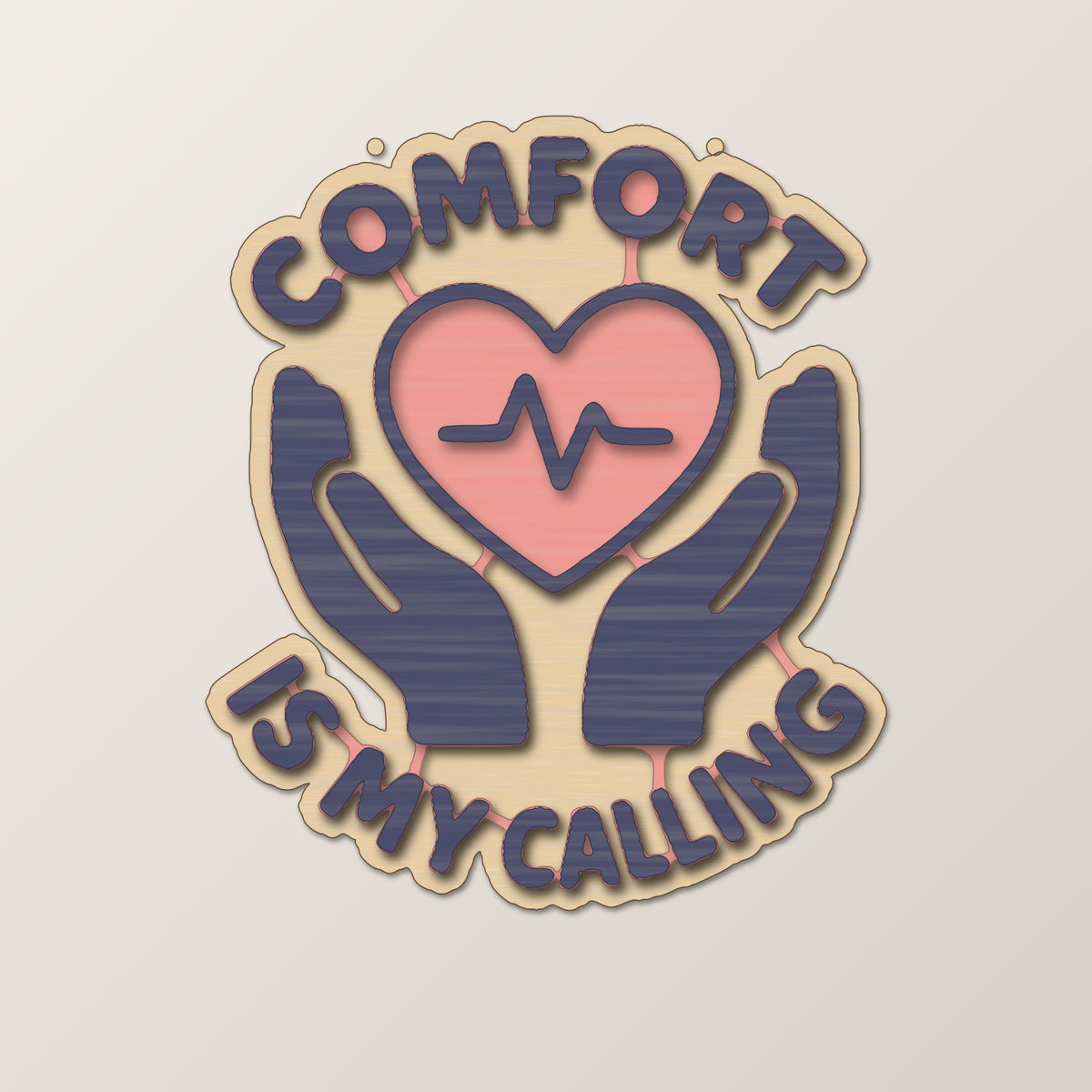 Round-edged wooden ornament with an engraved heart and pulse line held by two hands, with the words Comfort Is My Calling, hanging against a dark green blurred light background.