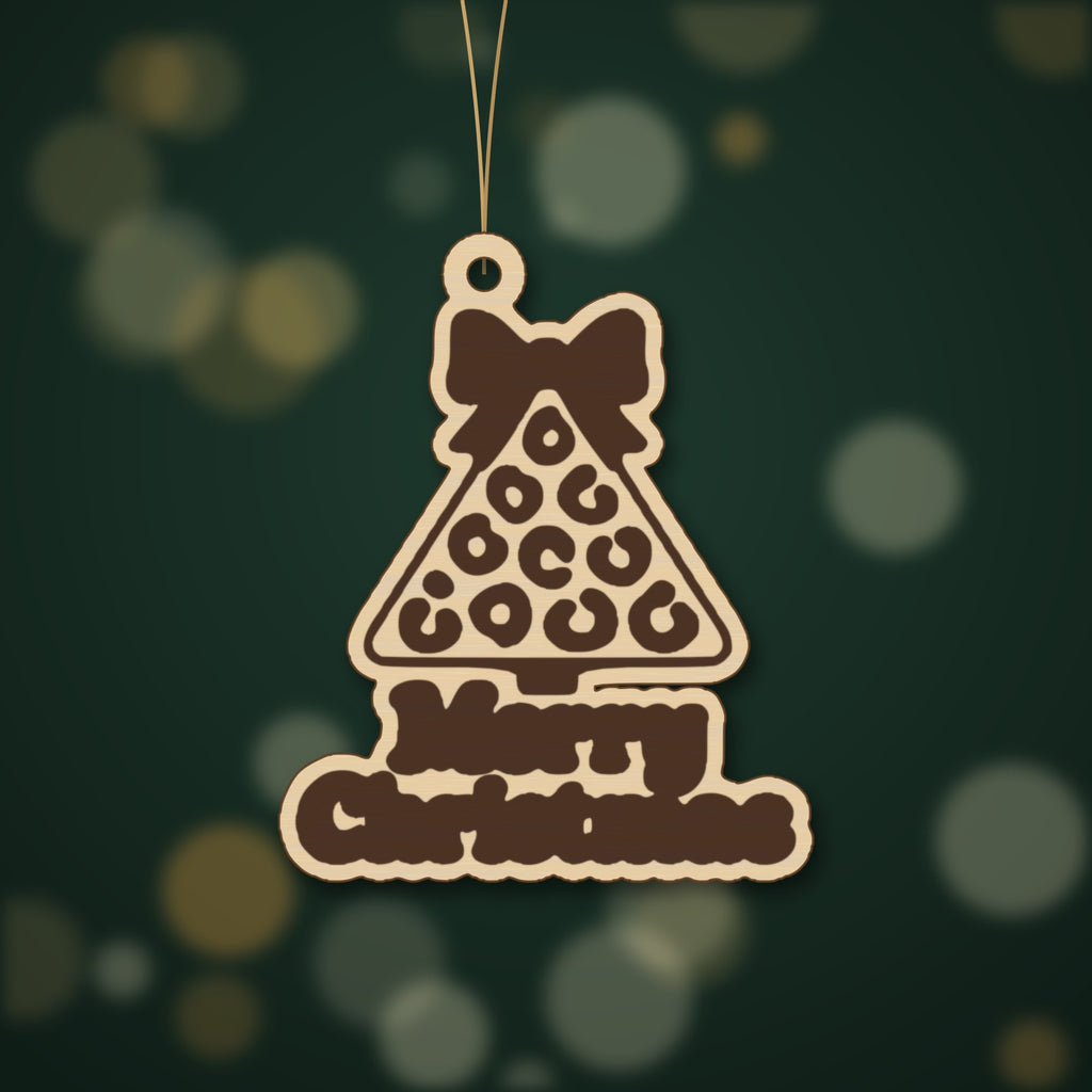 Laser cut wooden Christmas ornament shaped like a leopard print tree with a bow on top and the words Merry Christmas below, hanging against a dark green blurred background.