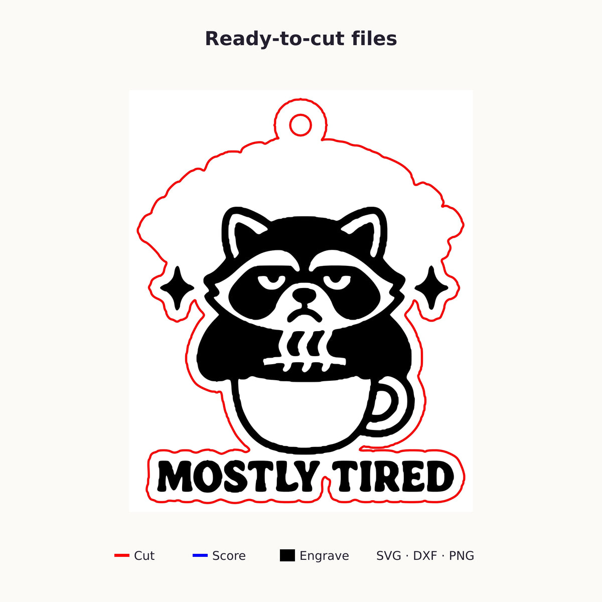 A laser-cut wooden ornament showing a grumpy raccoon sitting in a coffee cup with sparkles above it and the words Mostly Tired engraved underneath, hanging on a gold string against a dark green background.
