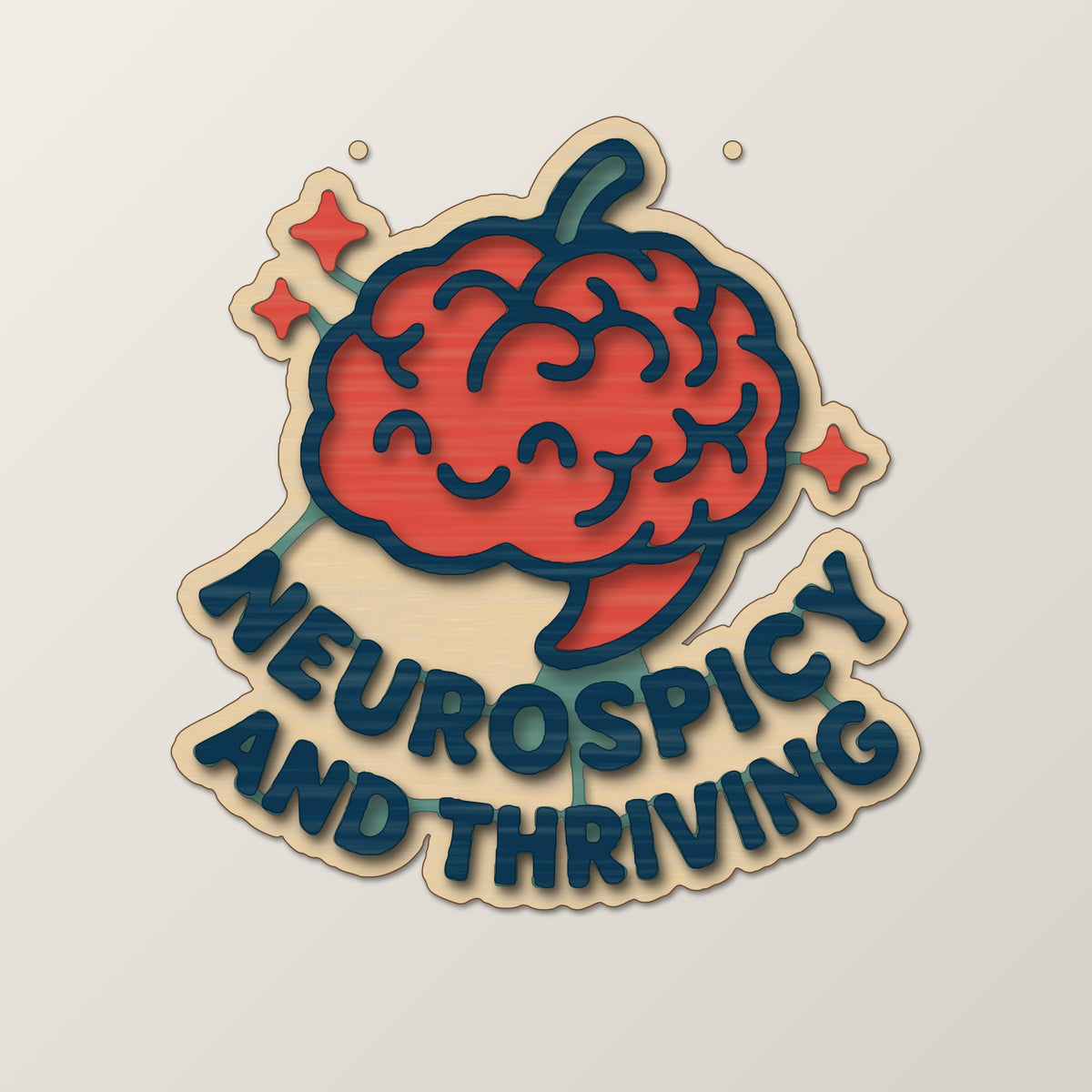 Wooden laser cut ornament with a dark brown engraved brain with a chili stem and the words Neurospicy and Thriving, hanging on a gold string against a green background with soft bokeh lights.