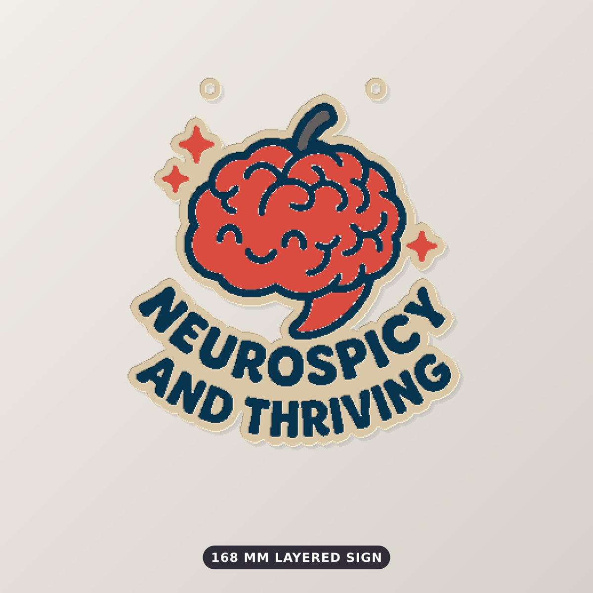 A 75 mm ornament of a smiling red chili-pepper brain with sparkles and the words Neurospicy and Thriving, hanging on a gold cord against a dark green bokeh background.