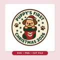 Round Christmas ornament design with a smiling puppy in a Santa hat peeking out of a red and green stocking, surrounded by paw prints and snowflakes, with the text Puppy's First Christmas 2026.