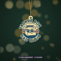 Round retro ornament showing an open tackle box on a striped sunset circle with the words Tackle Box Dad Club around the edge, hanging against a dark green background with golden bokeh lights.