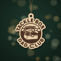 Round wooden laser engraved ornament with a retro tackle box and fishing lure badge and the words Tackle Box Dad Club, hanging on a thin cord against a dark green background with soft golden lights.