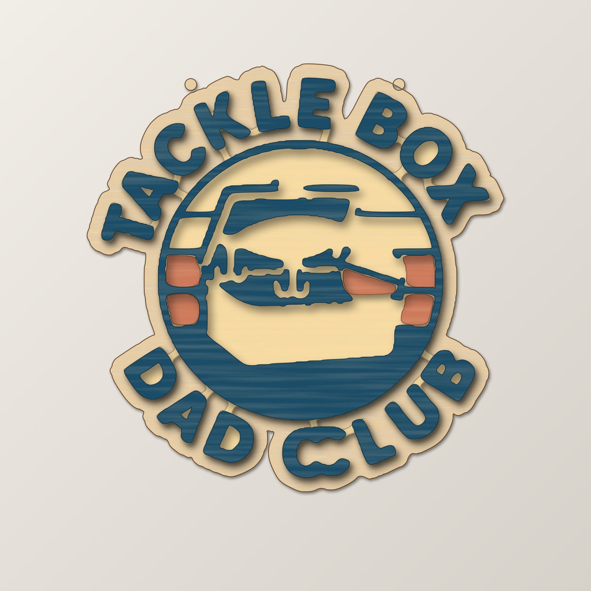Round wooden laser engraved ornament with a retro tackle box and fishing lure badge and the words Tackle Box Dad Club, hanging on a thin cord against a dark green background with soft golden lights.