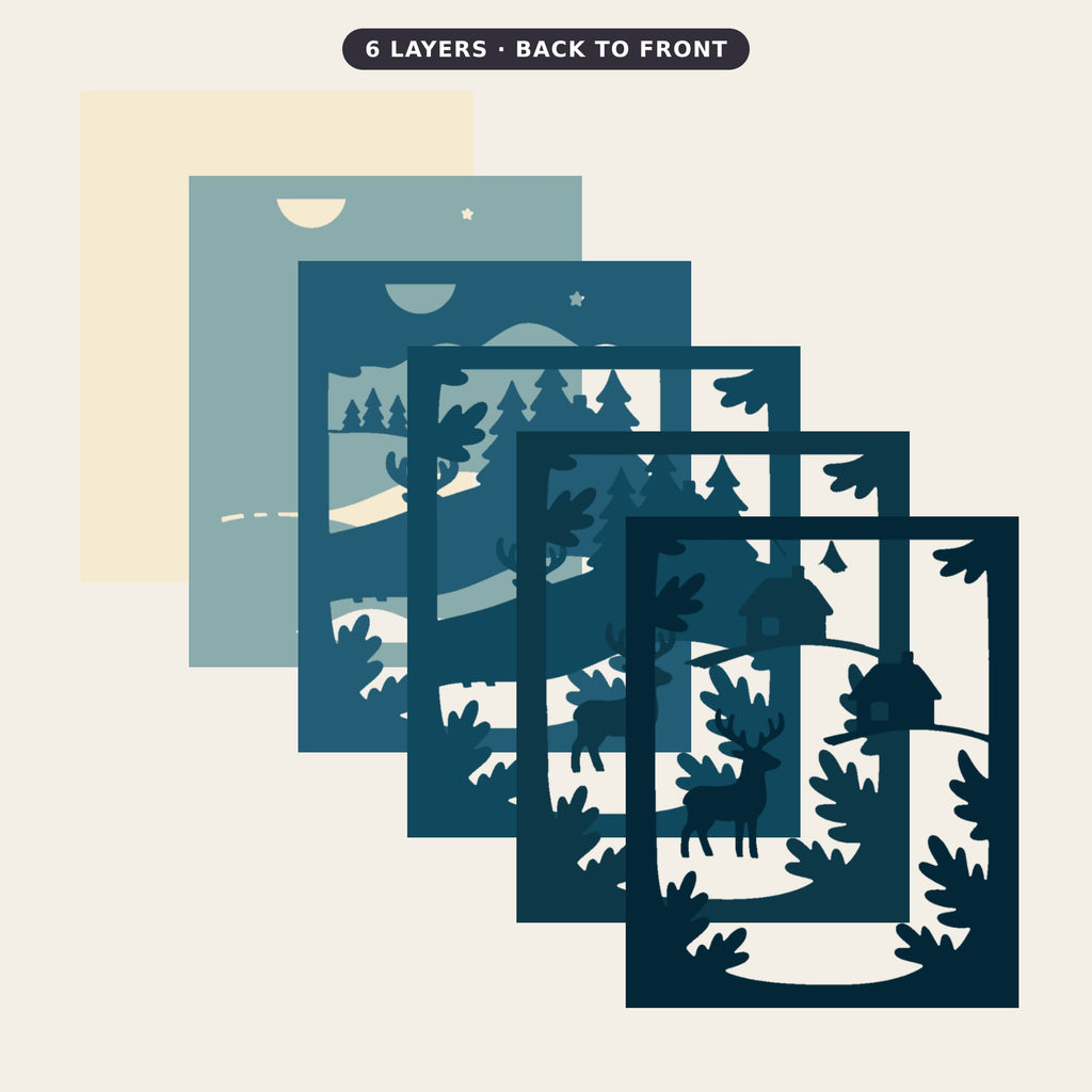 Layered papercut shadow box in deep blues and cream showing a stag standing on a snowy hill in front of a cabin, pine trees, a moon and a star at night.