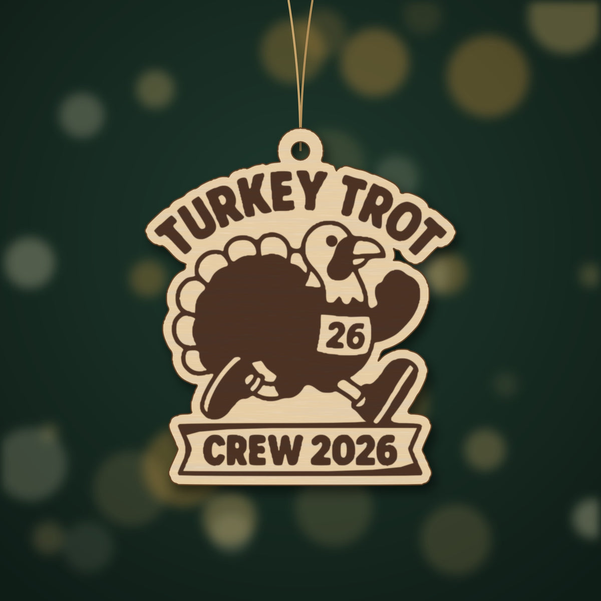 A laser cut wooden ornament showing a cartoon turkey running in a race bib numbered 26, with the words Turkey Trot above and Crew 2026 on a banner below, hanging against a dark green background.