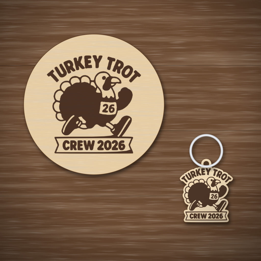 A laser cut wooden ornament showing a cartoon turkey running in a race bib numbered 26, with the words Turkey Trot above and Crew 2026 on a banner below, hanging against a dark green background.
