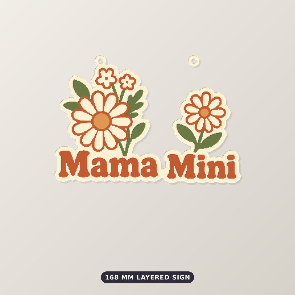 Retro floral ornament with cream and orange wildflowers and rust-red "Mama Mini" lettering, hanging from a gold string against a dark green background, labeled 75 mm ornament, 4 colors.